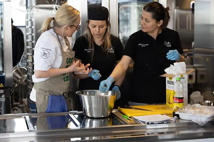 Tre personer i ett kök. 