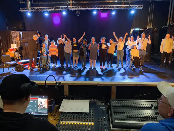 En grupp människor på en scen. I förgrunden ett ljusbord.