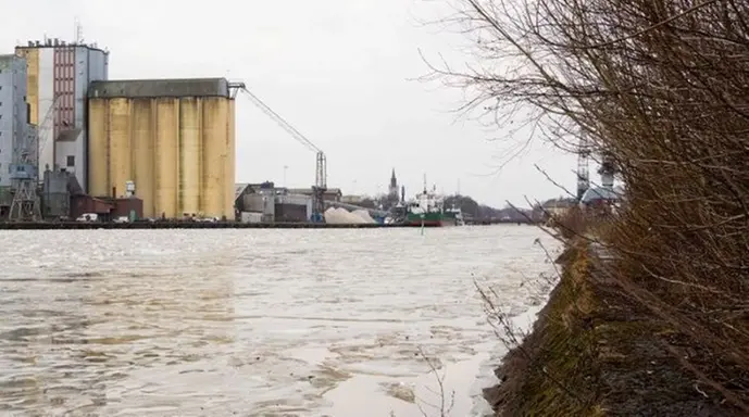 En bild på vattnet i ån Lidan. Industrier och stadsmiljö i bakgrunden.