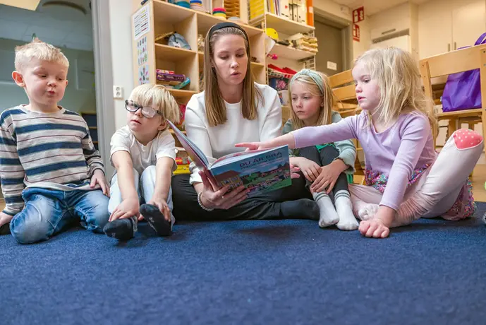 Förskolelärare läser för barn. 
